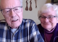 Bob and Marj Folkestad smiling at the screen. Both have glasses and white hair.