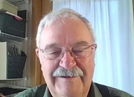 Daniel Yuhas with curtains and bookshelf in background