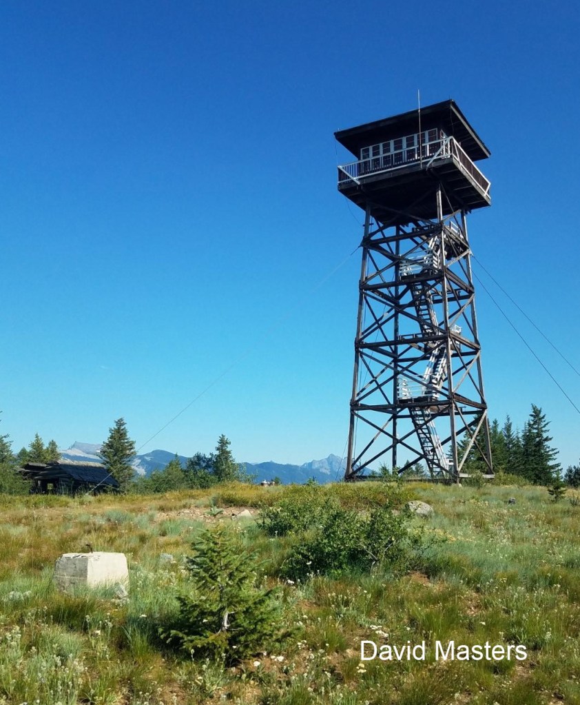 A tower lookout with a blue sky and mountains in the background.