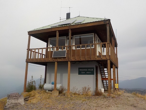 A two-level lookout on top of a mountain with clouds in the background.